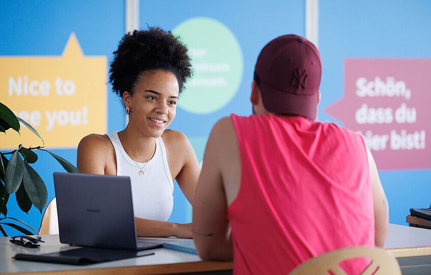 Zwei Studierende sitzen einander im Gespräch gegenüber